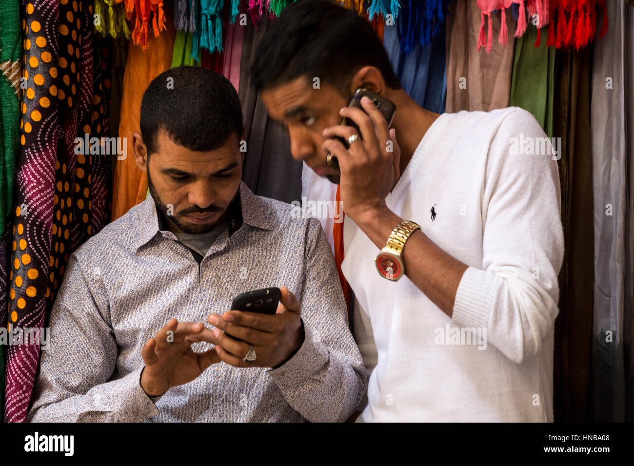 Rissani, Marokko.  Markt, zwei junge Männer, die Nutzung von Mobiltelefonen. Stockfoto