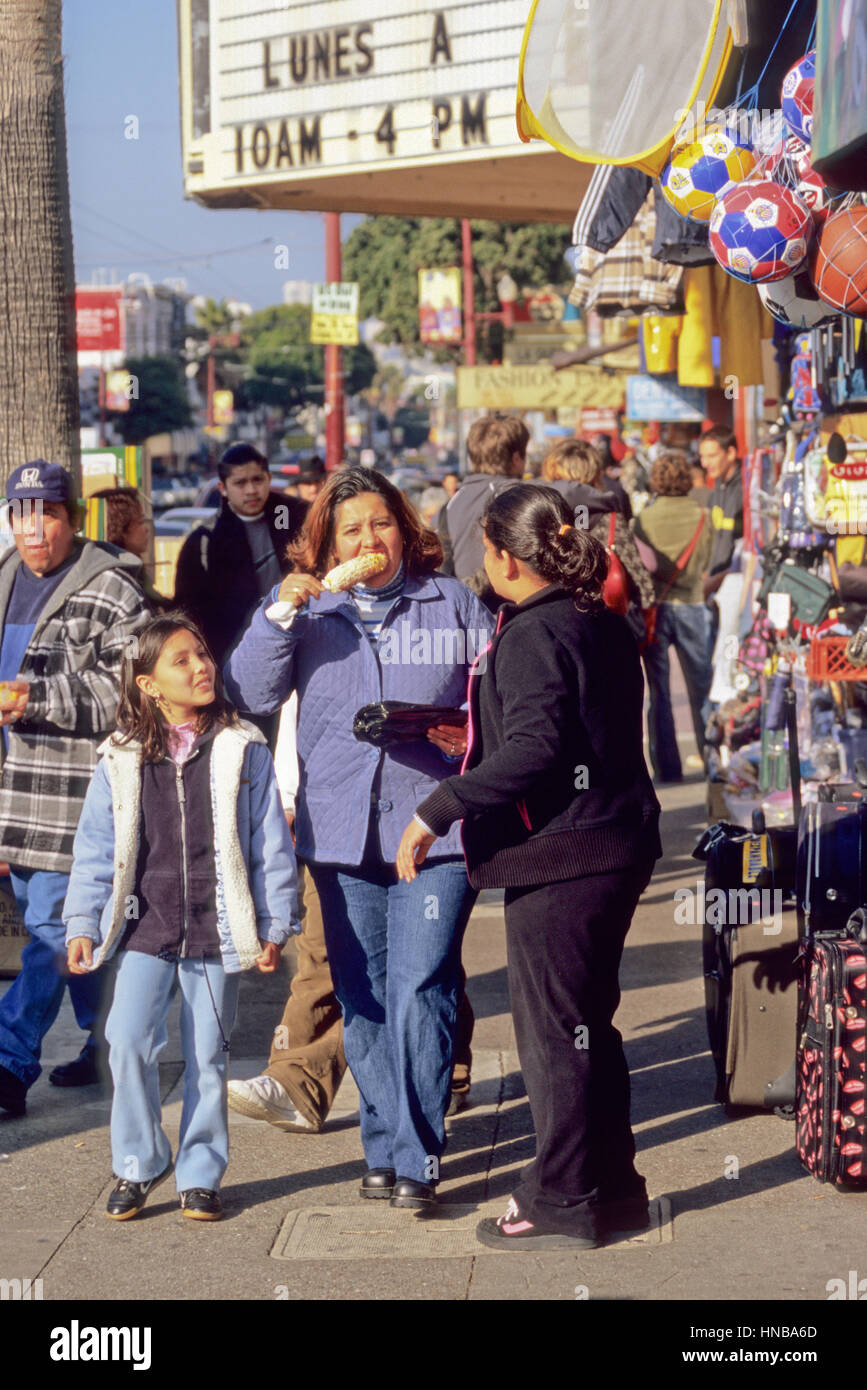 San Francisco, Kalifornien.  Mission Street Fußgänger, Mission District.  Woman Eating Corn on the Cob. Stockfoto