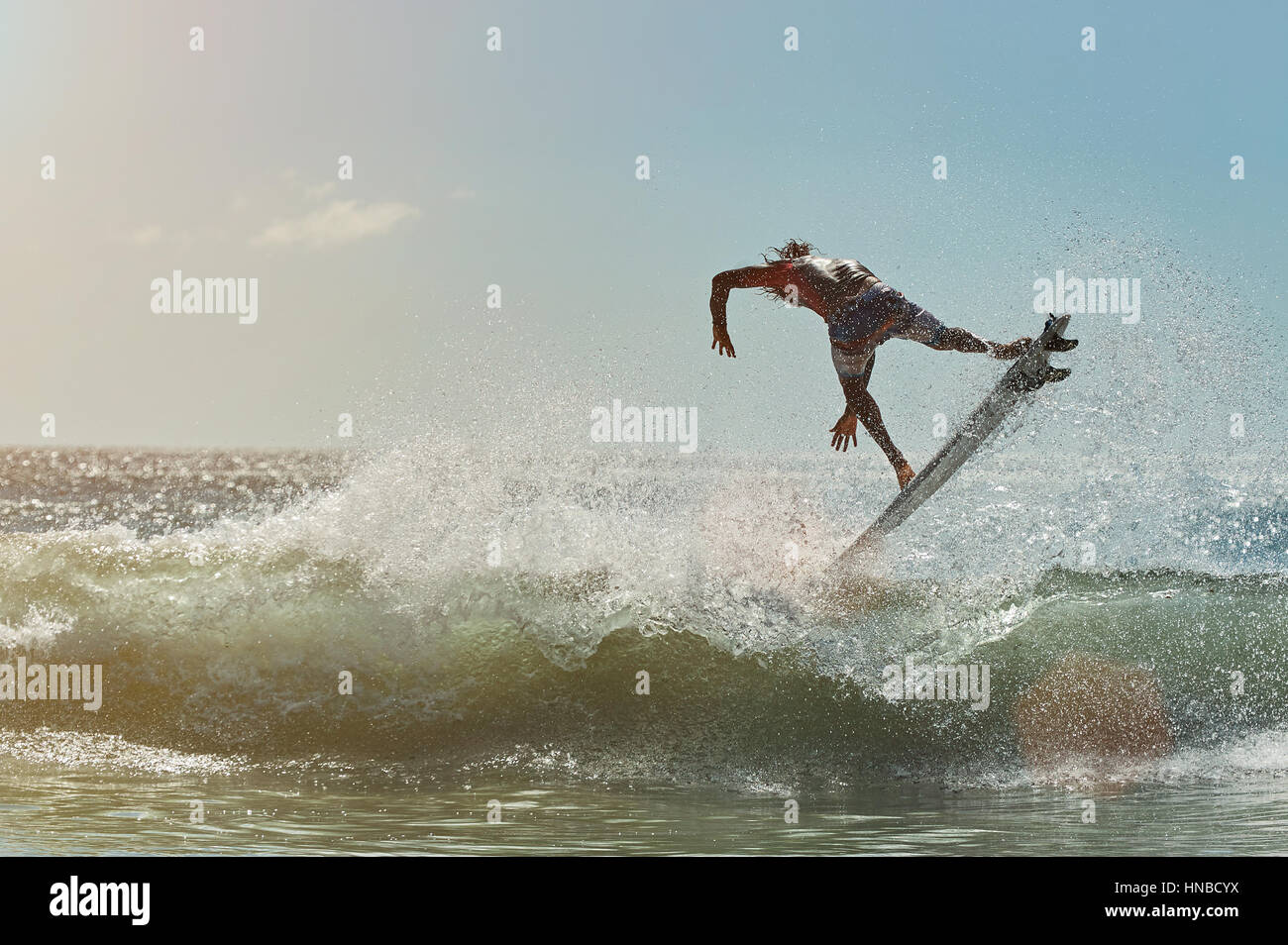 Surfer auf Wasserwelle im Ozean sonnigen Tag springen Stockfoto