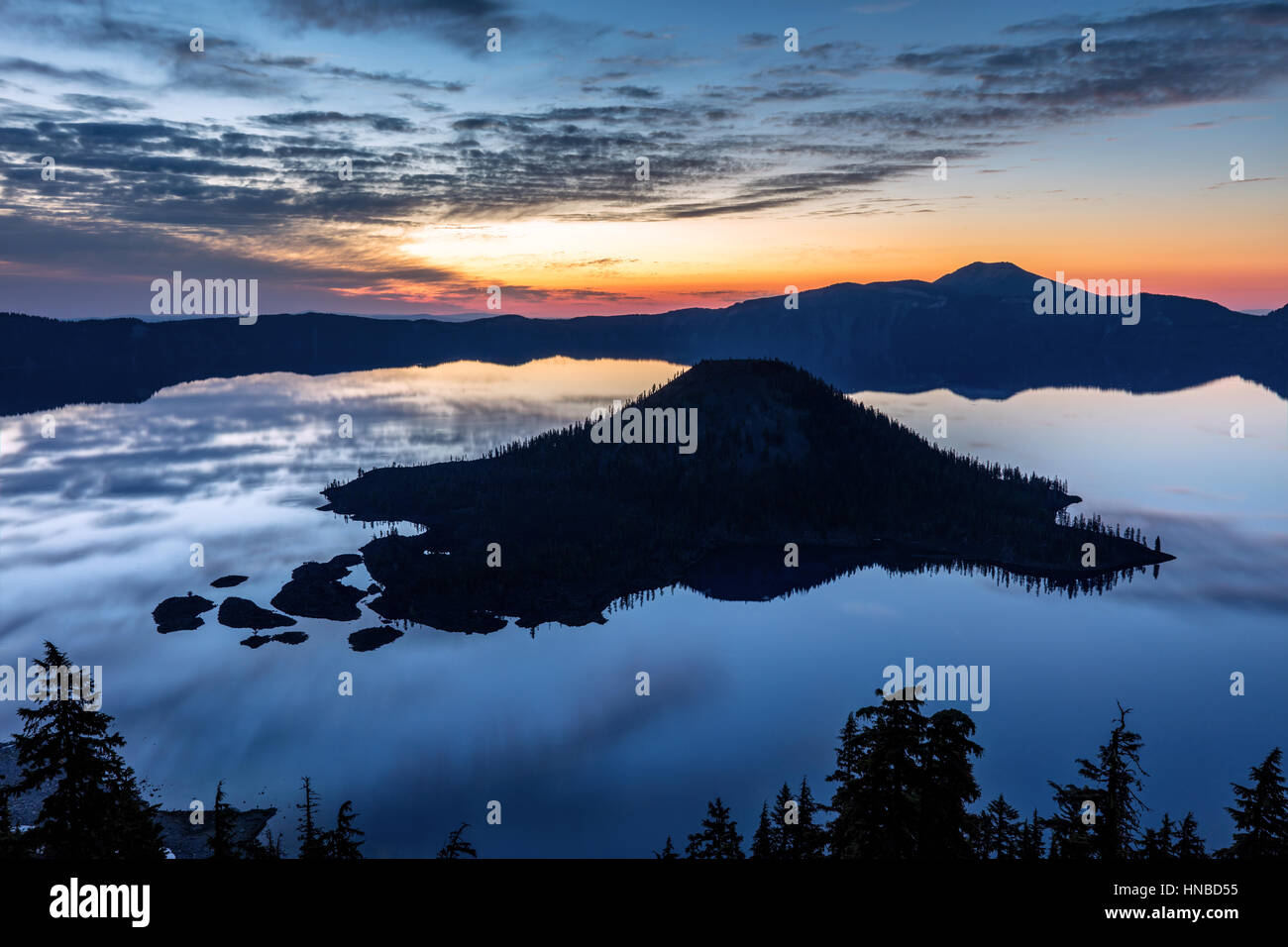 Der Assistent in der Morgendämmerung. Verträumte Landschaft nur vor Sonnenaufgang in Crater Lake mit eine markante Silhouette des Assistenten Insel und Reflexion von Himmel und Wolken Stockfoto