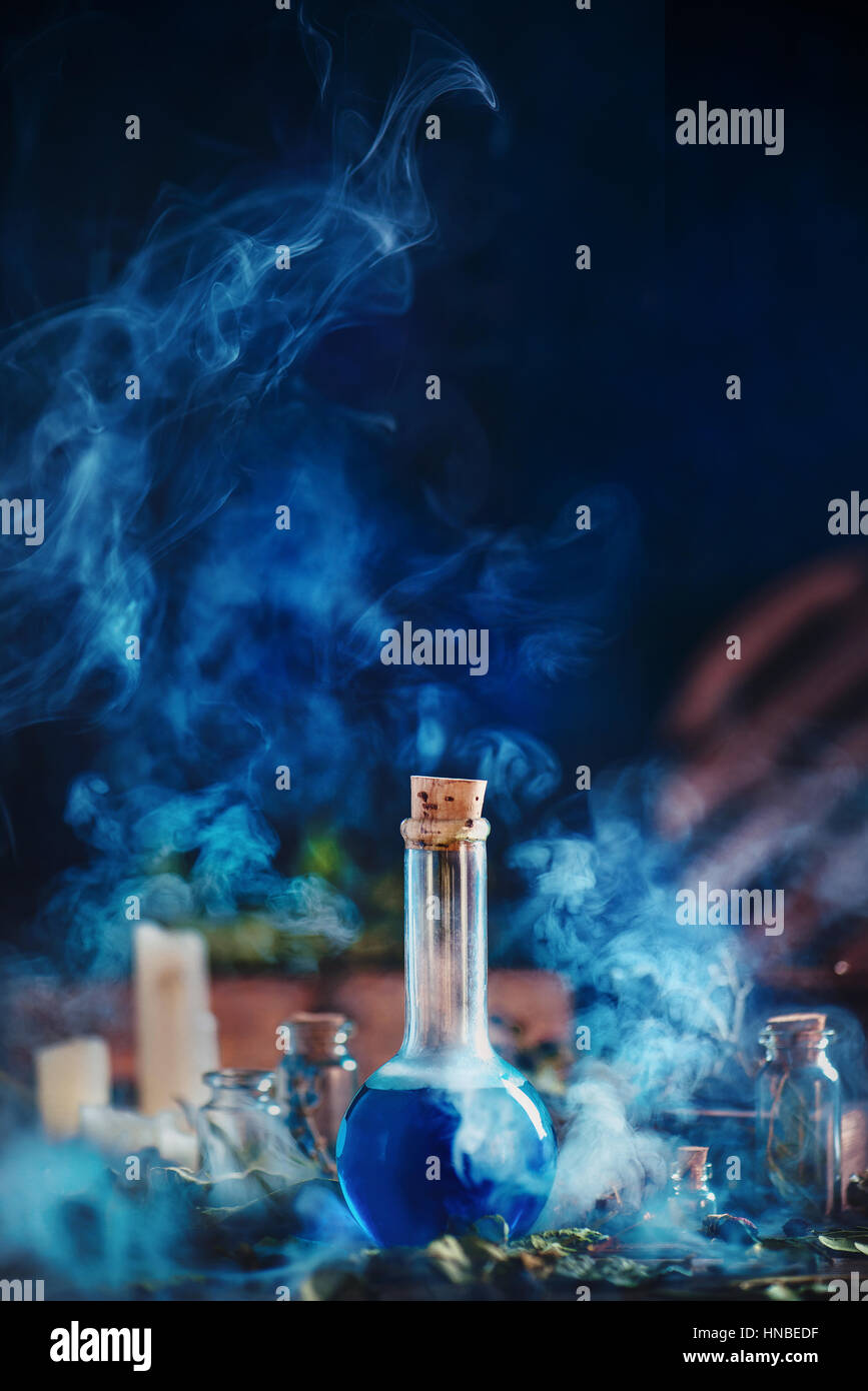Glasflasche mit blauer Flüssigkeit und dicken Wolken steigenden Rauch auf dunkelblauem Hintergrund Stockfoto
