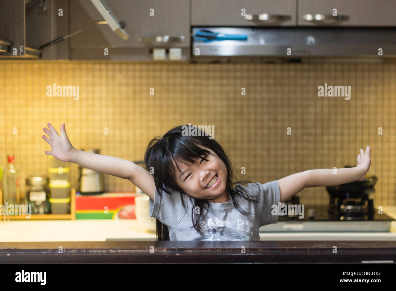 Lächelndes Mädchen mit ausgestreckten Armen in Küche Stand Stockfoto