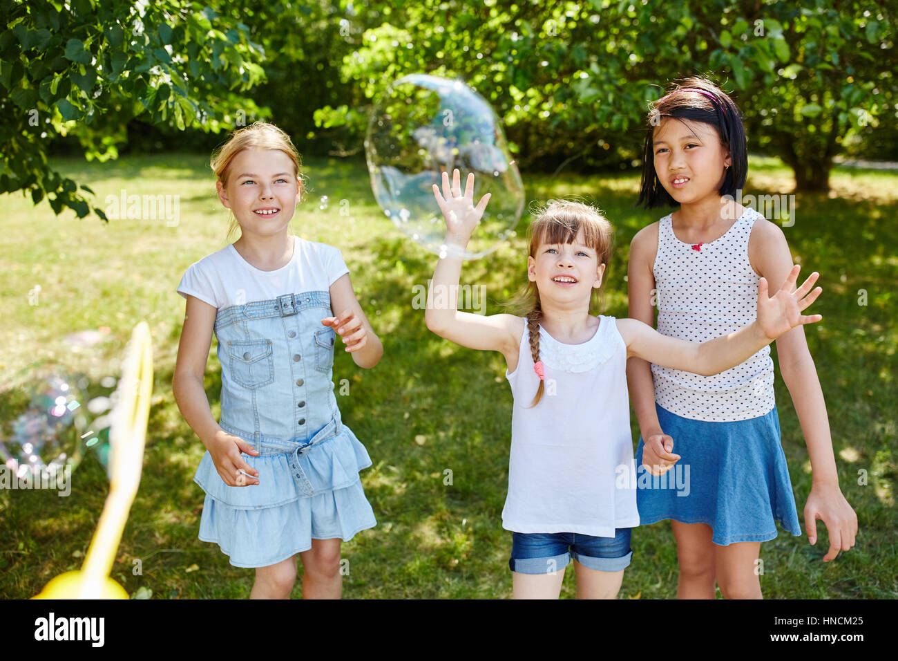 Kinder spielen fangen Seifenblasen im Sommer in der Natur Stockfoto