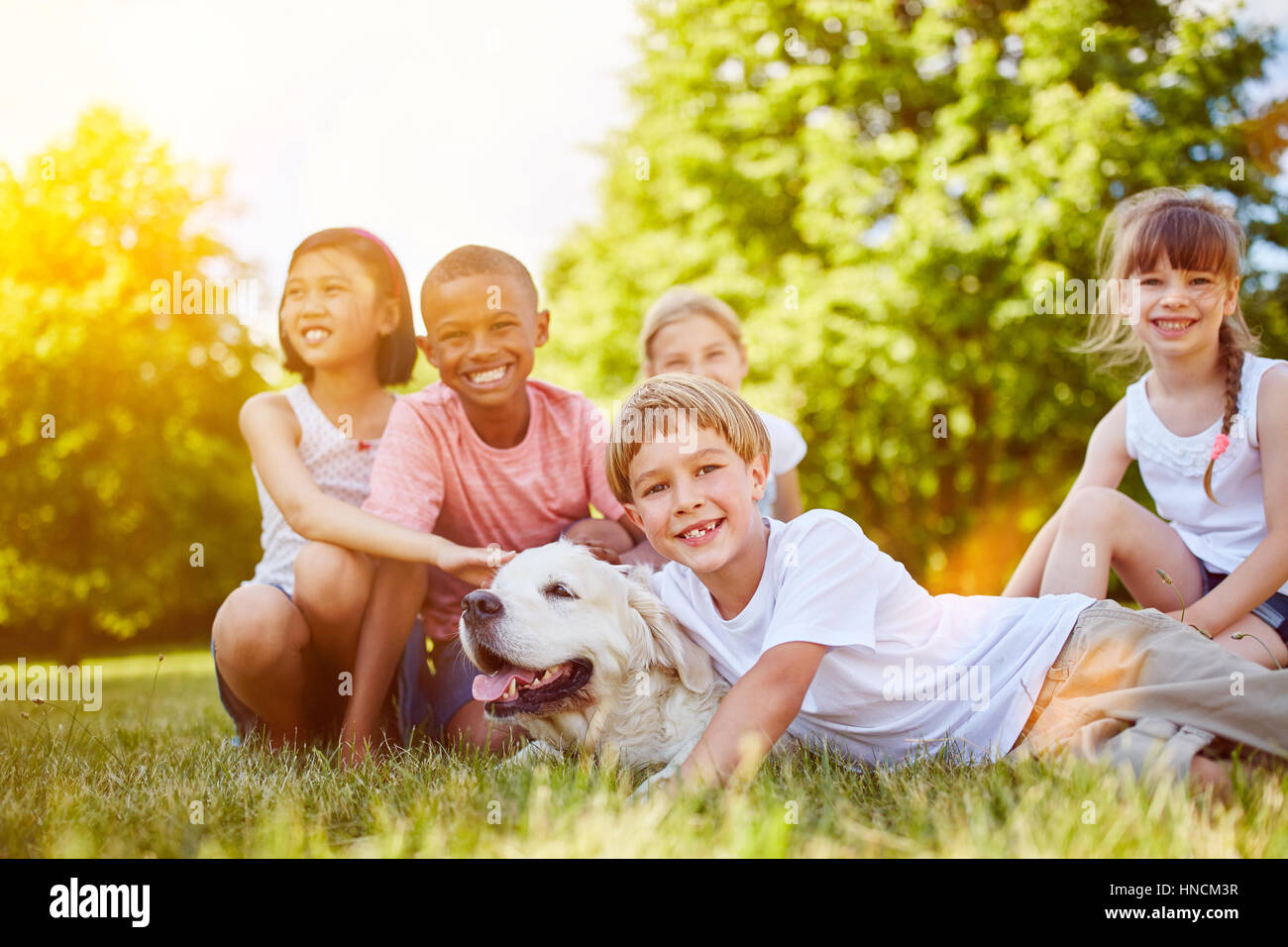 Glückliche Gruppe von Kindern mit Golder Retriever im park Stockfoto