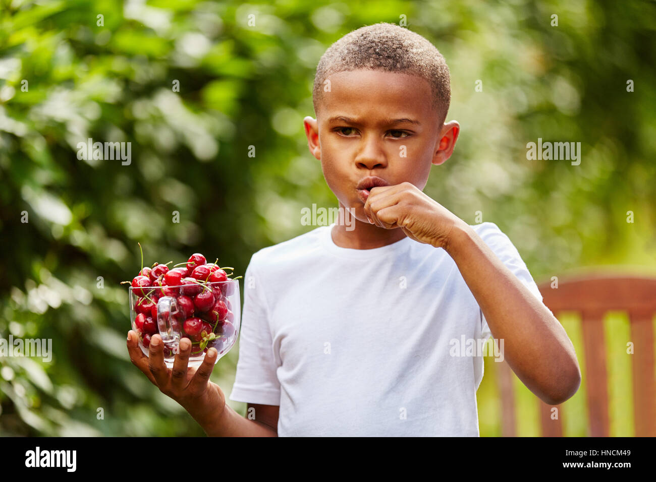 Afrikanische Kind isst Kirschen als gesunde Obst im Garten Stockfoto