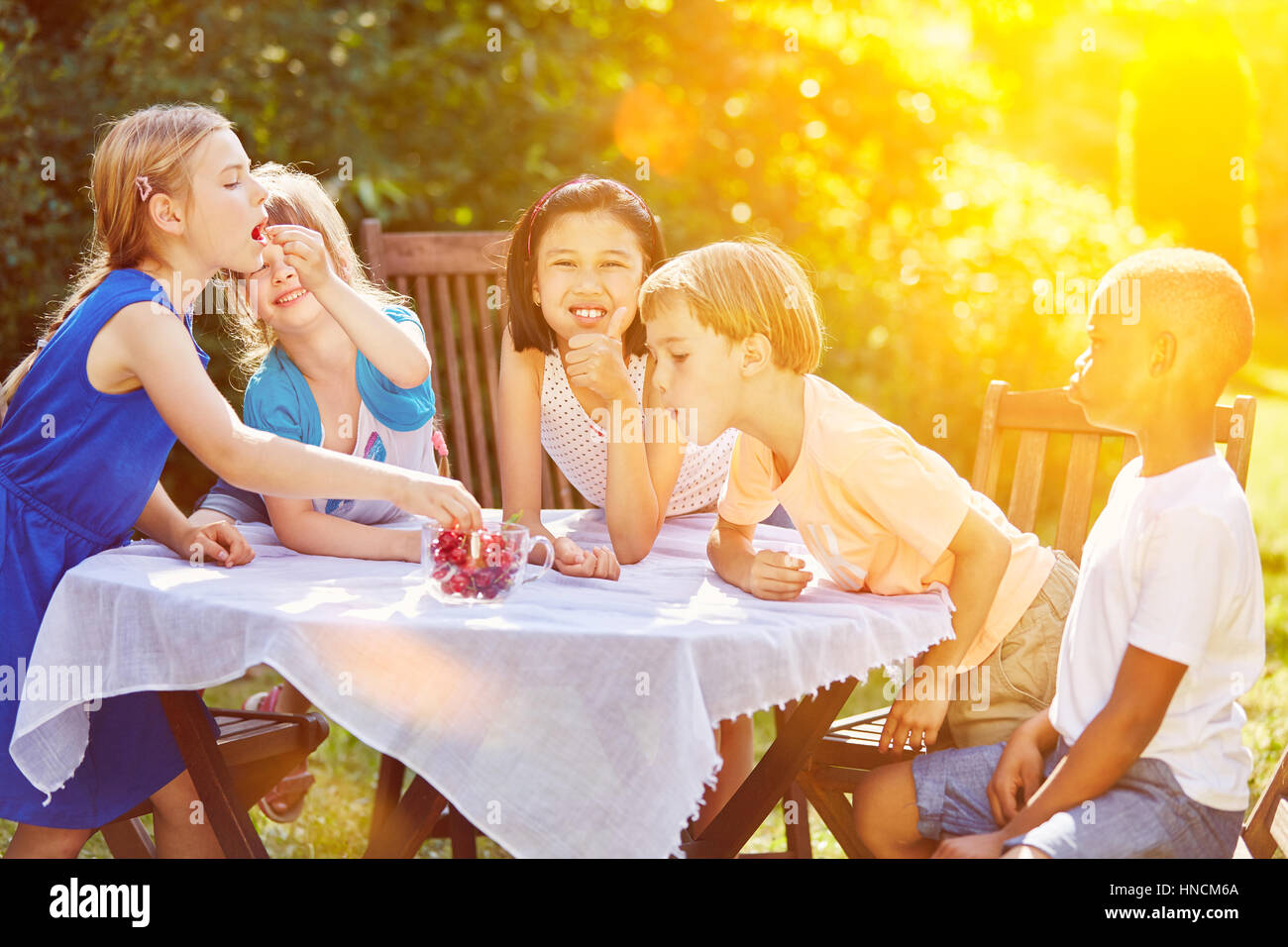 Gruppe von Kindern im Garten im Sommer Kirschen essen Stockfoto