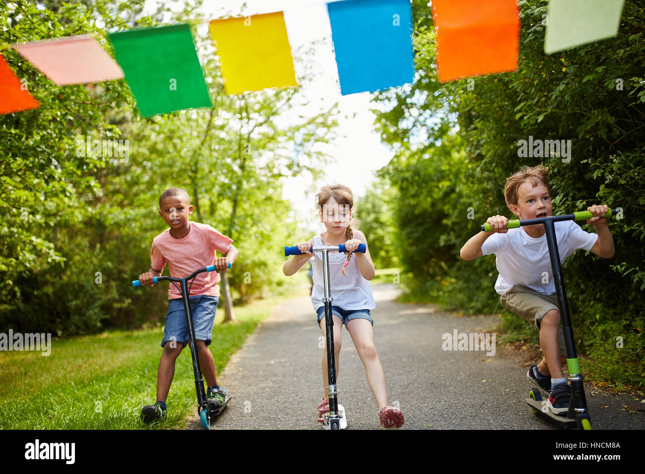 Kinder Spaß-Rennen im Park mit Scooter im Sommer Stockfoto