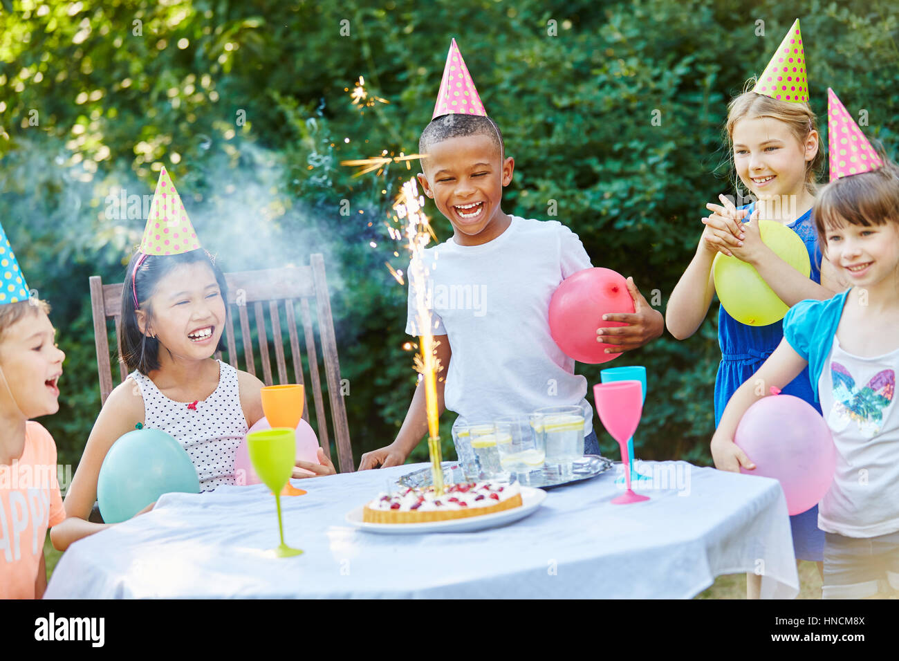 Kinder feiern Geburtstagsparty mit Tisch-Feuerwerk auf Kuchen Stockfoto