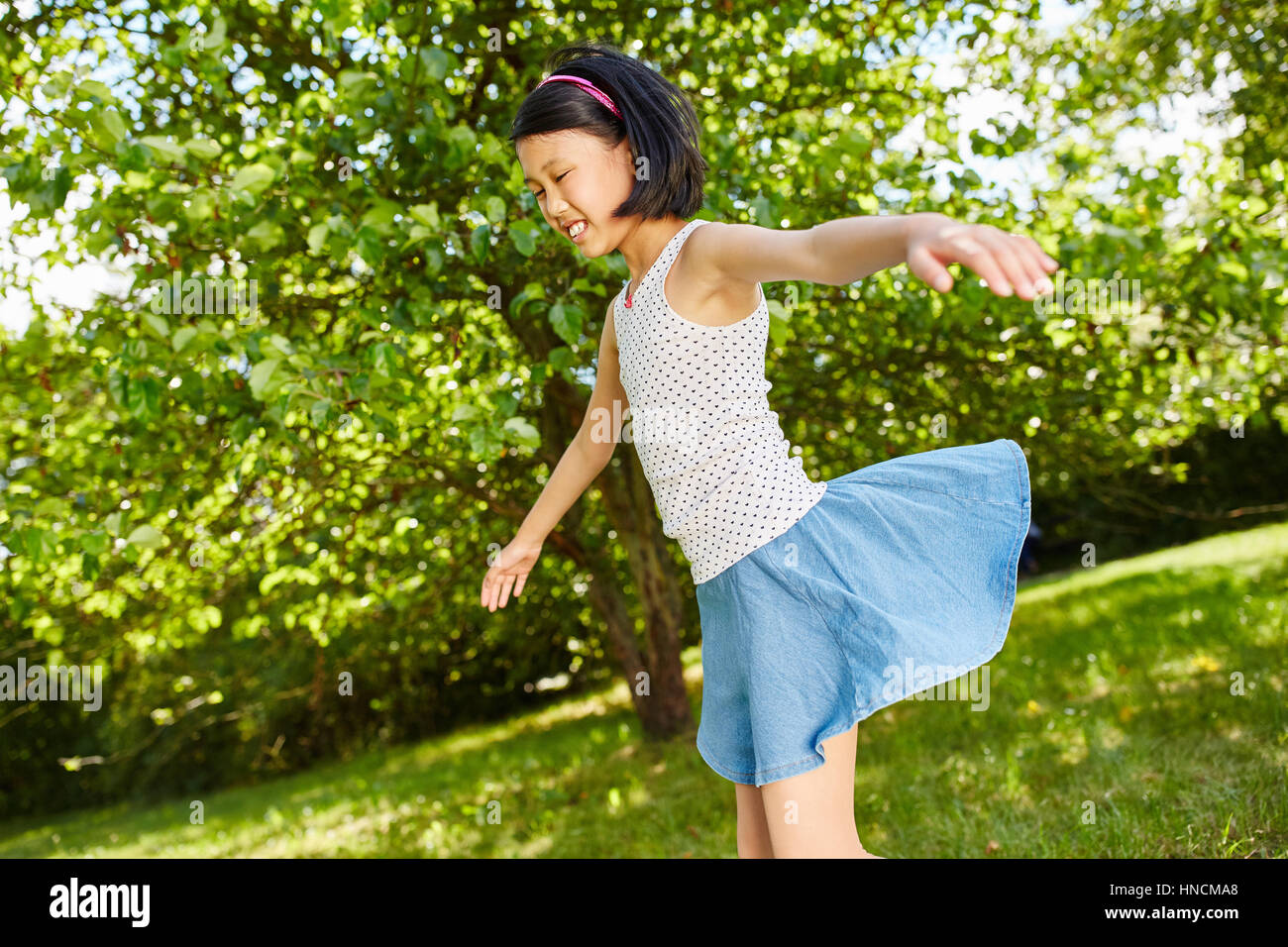 Asiatische Mädchen spielen und tanzen im Sommer in der Natur im park Stockfoto
