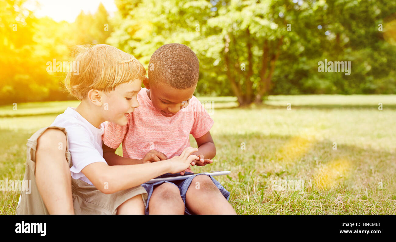 Zwei interracial jungen haben Spaß mit Tablet im Park im Sommer Stockfoto