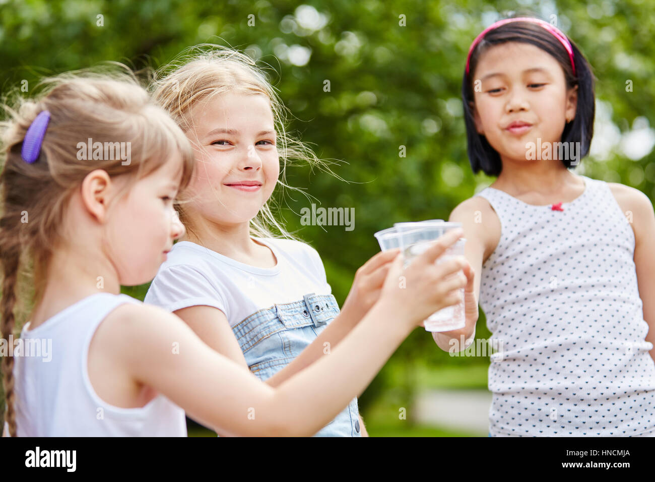 Drei Mädchen trinken Wasser und Klirren der Gläser im Sommer Stockfoto