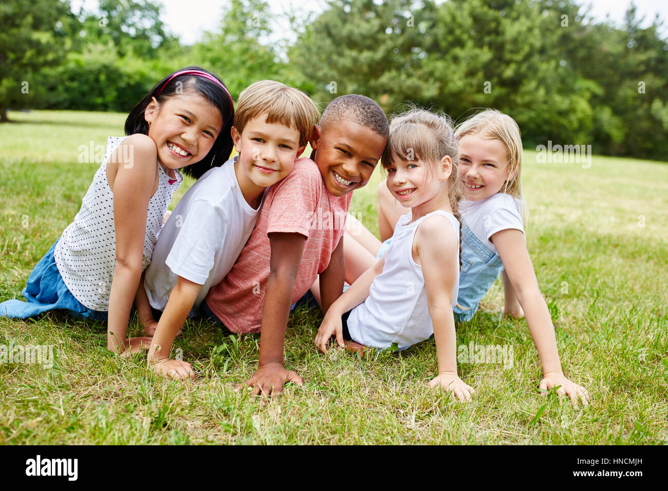Glückliche interracial Kinder als Freunde sitzen zusammen im