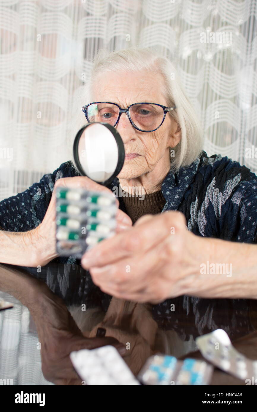 Oma mit Lupe Medikament Namen ermitteln Stockfoto