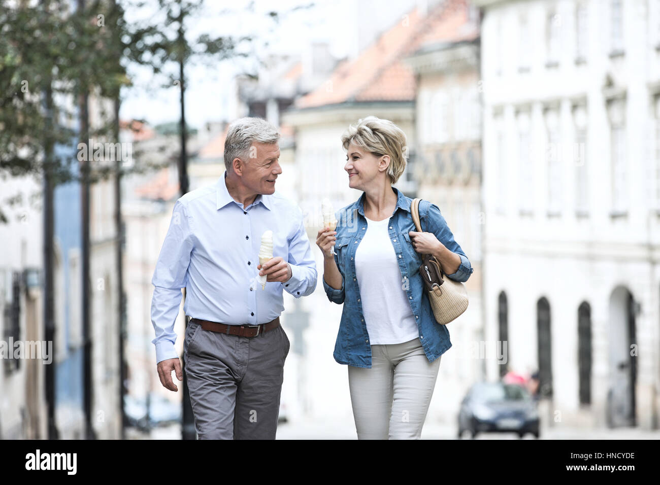 Glückliches Ehepaar mittleren Alters sahen einander haltend Eistüten in Stadt Stockfoto