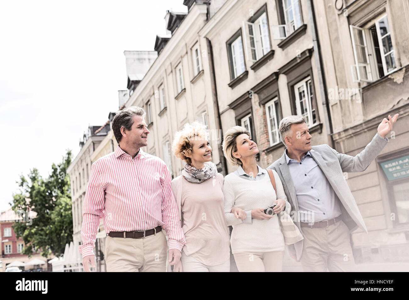 Mann mittleren Alters zeigen etwas an Freunde während des Gehens in Stadt Stockfoto