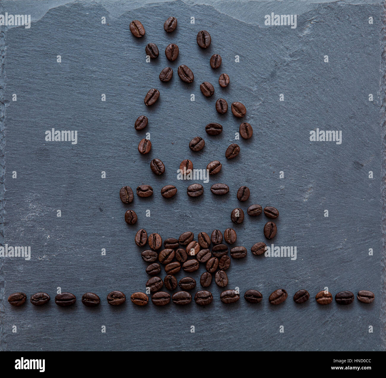 Kaffeebohnen auf grauem Stein geformt als Kaffeetasse gefüllt mit Kaffee, Rauchen, künstlerische Darstellung Konzept Stockfoto