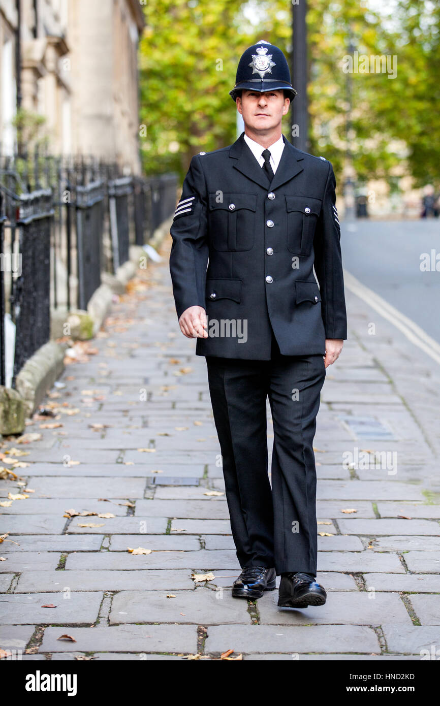 Ein elegant gekleideter englischer Polizist in voller Uniform patrouilliert auf seinem Beat, der entlang einer viktorianischen Straße in Bath, England, läuft Stockfoto