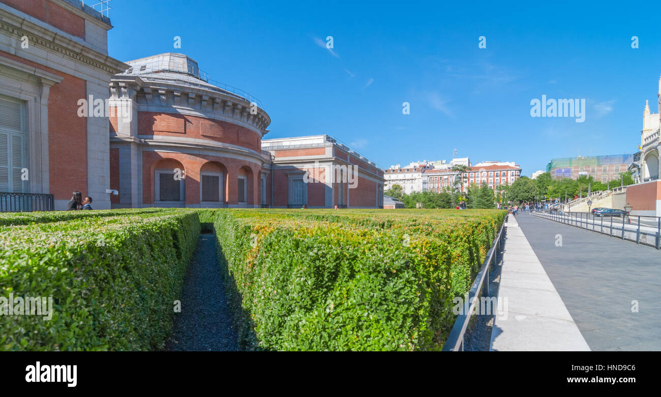 Madrid, Spanien - 9. November 2013: Tourismus in Spanien.   Ein paar genießen Sie Sonne, nah beieinander in einem Garten von ordentlich gepflegt, Diagonale Reihen von Büschen. Stockfoto