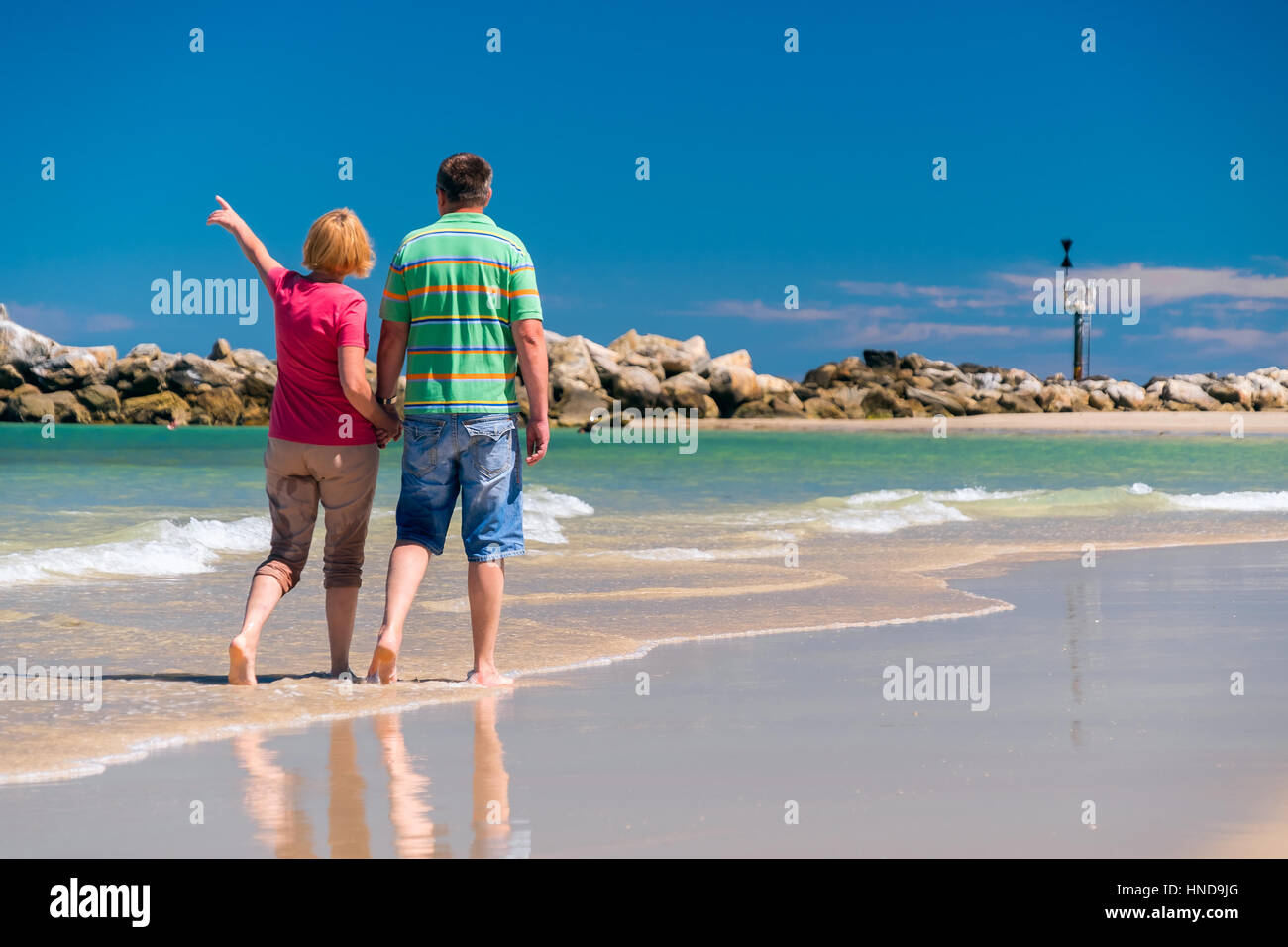 Älteres Paar zu Fuß am Strand Hand in Hand der jeweils anderen Stockfoto