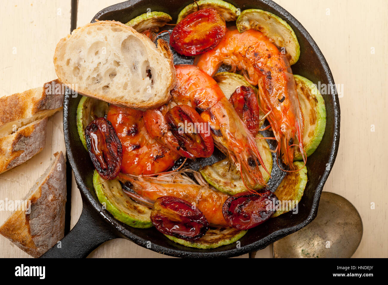 Gebratene Garnelen auf gusseisernen Pfanne mit Zucchini und Tomaten Stockfoto