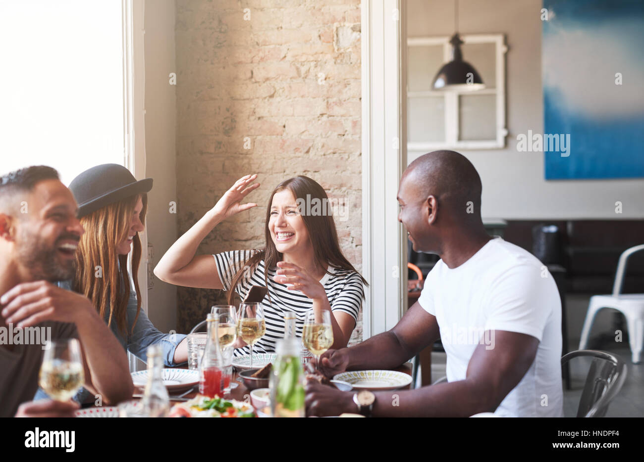 Gruppe von vier attraktiven Freunden am Tisch essen und Spaß beim Gespräch in hellen, modernen Café. Stockfoto