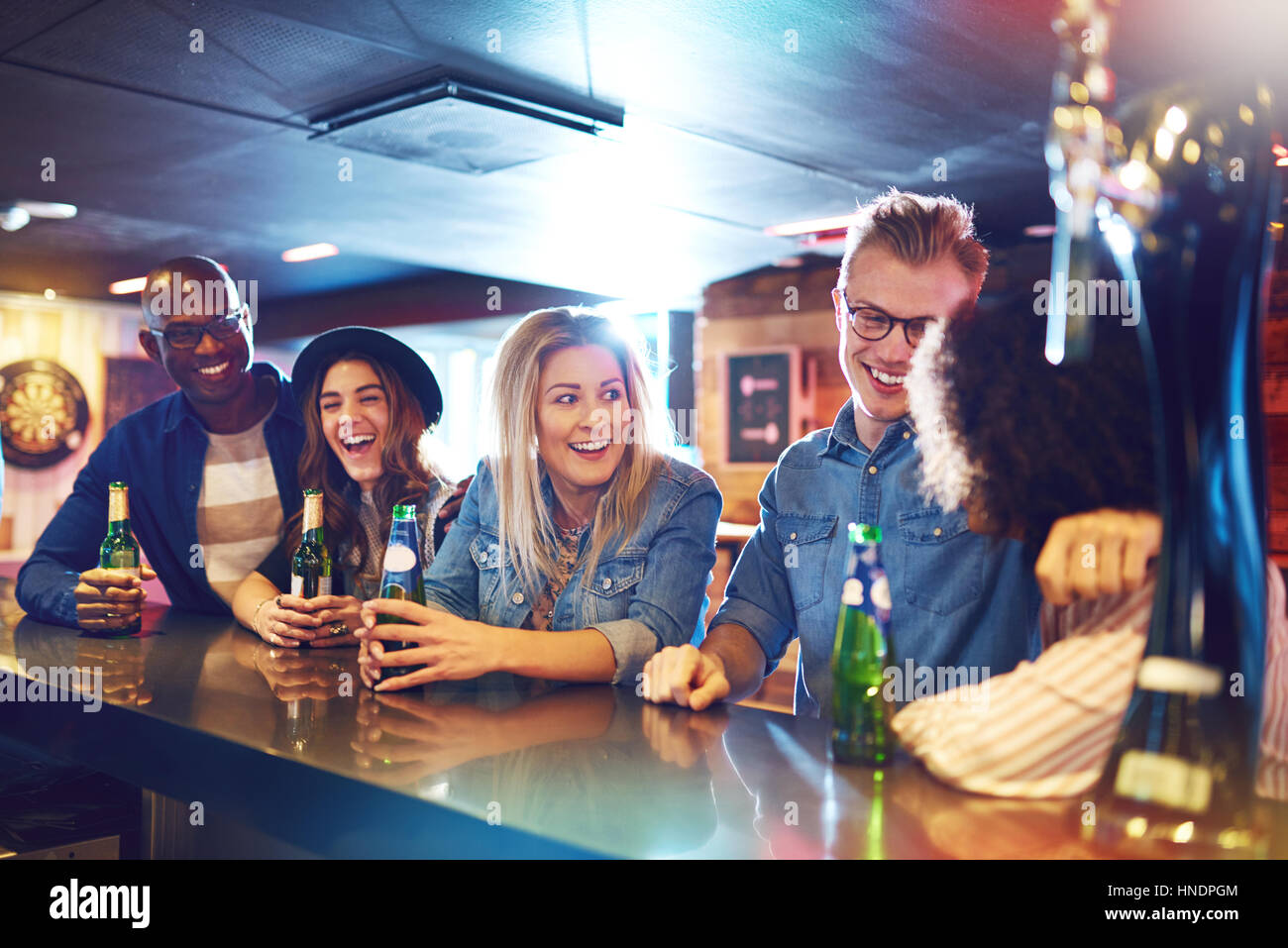 Ein Unternehmen der jungen Freunde mit dem Bier in der Bar im Gespräch. Horizontal im Haus erschossen. Stockfoto