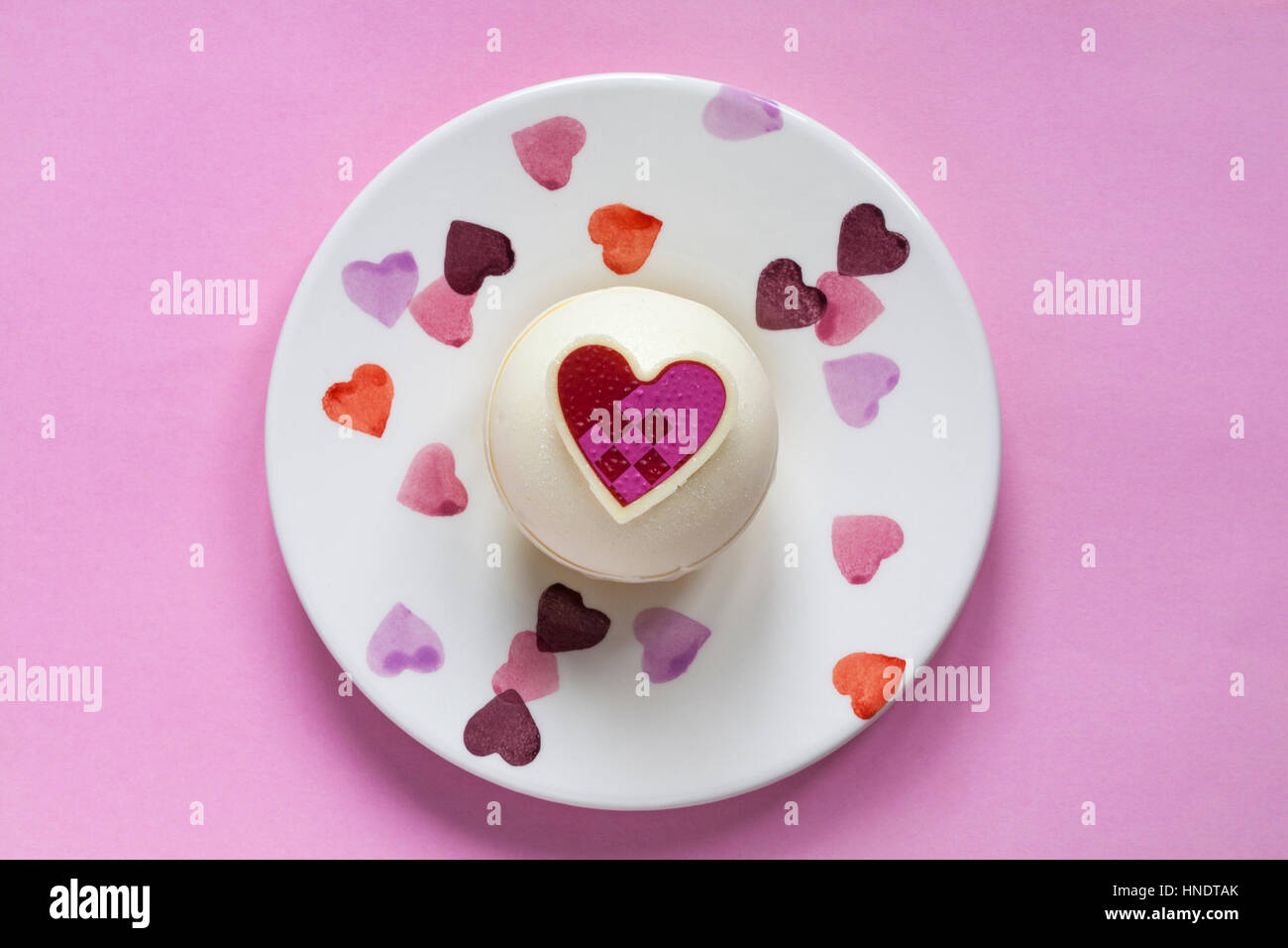 Schaut auf M & S Himbeere und Prosecco Kugeln zum Nachtisch zum Valentinstag auf dekorative Platte mit Herzen auf rosa Hintergrund Stockfoto