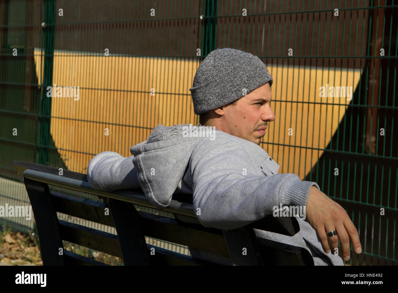 Junger Mann auf einer Bank sitzend Stockfoto