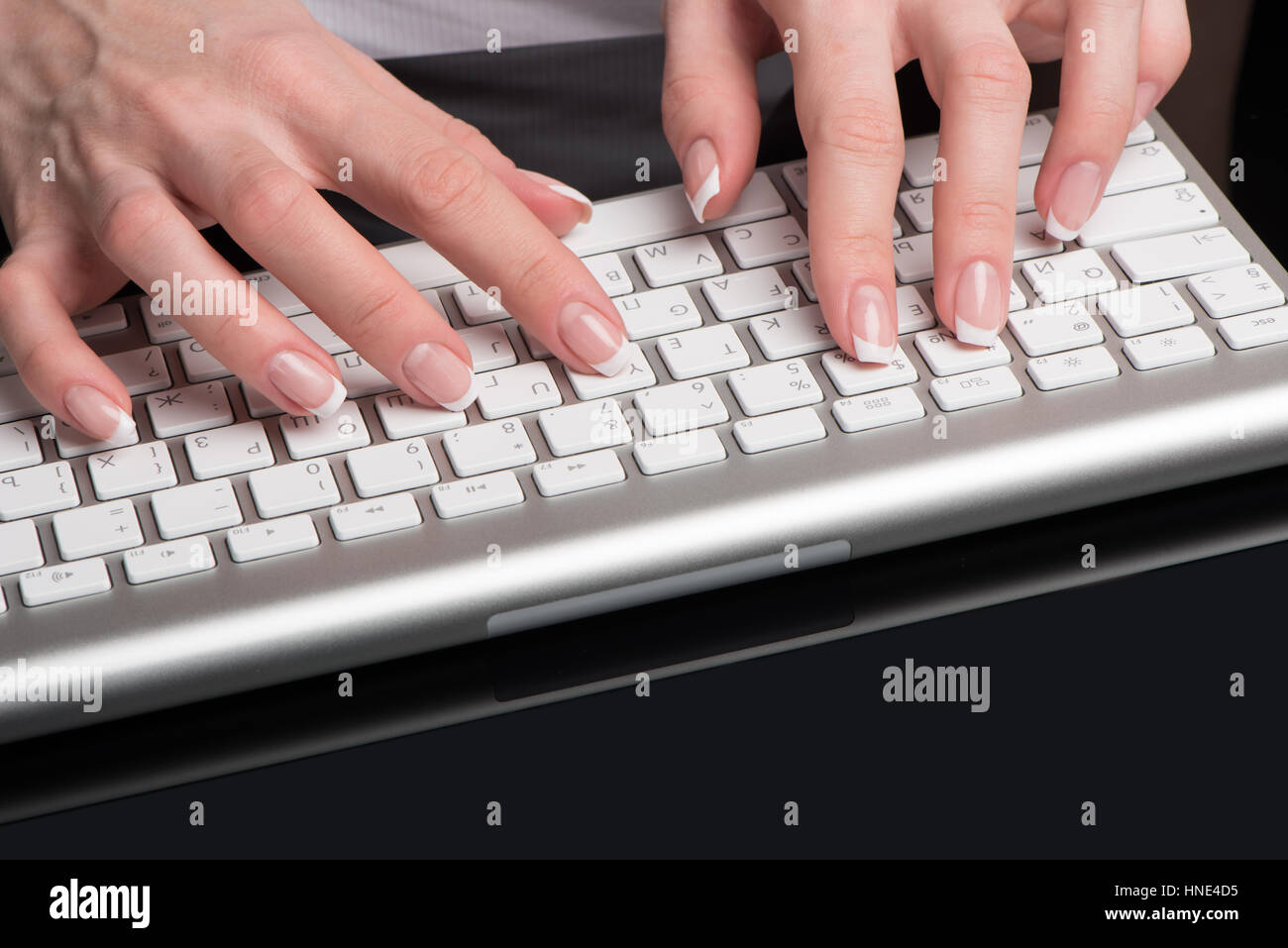 Weibliche schöne Hände mit klassischen French Maniküre befinden sich auf der Computer-Tastatur Stockfoto