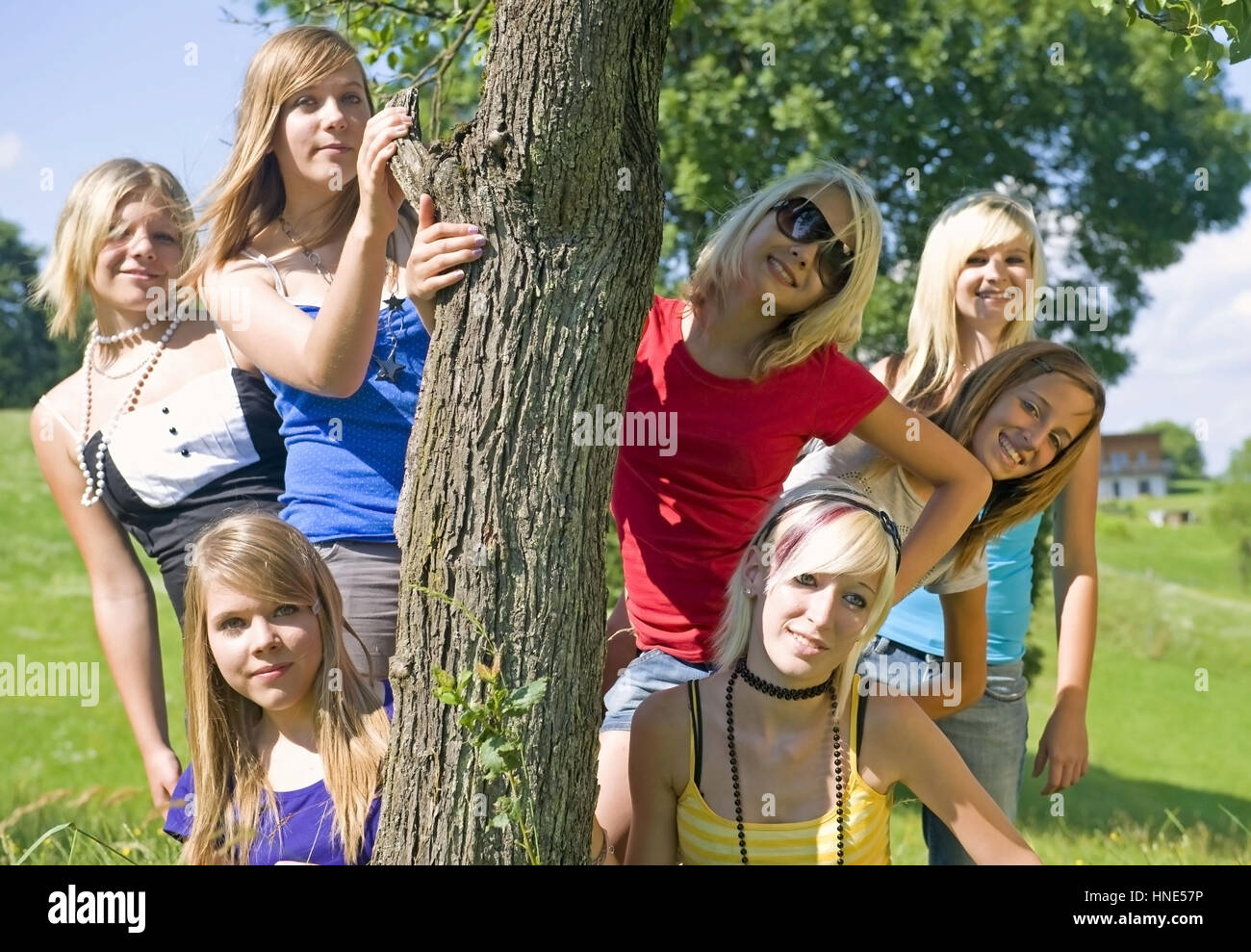 Model Release, Jugendliche Maedchen Stehen um Einen Baumstamm in der Wiese - Mädchen im Teenageralter Stockfoto