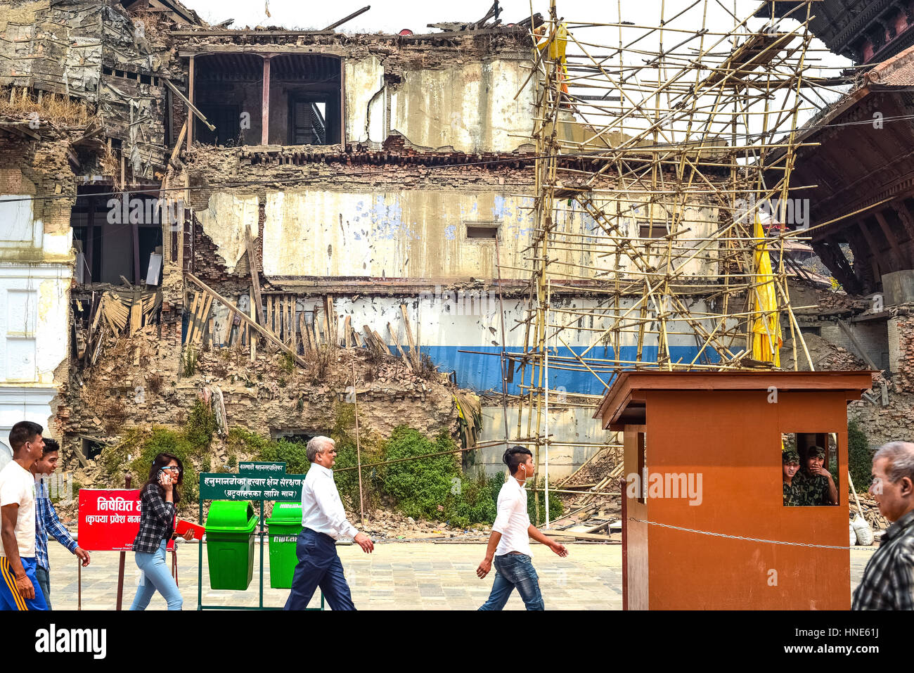 Die Einheimischen gehen vor beschädigte Gebäude in der Nähe von Hanuman Dhoka, Durbar Square, Kathmandu, Nepal. Stockfoto