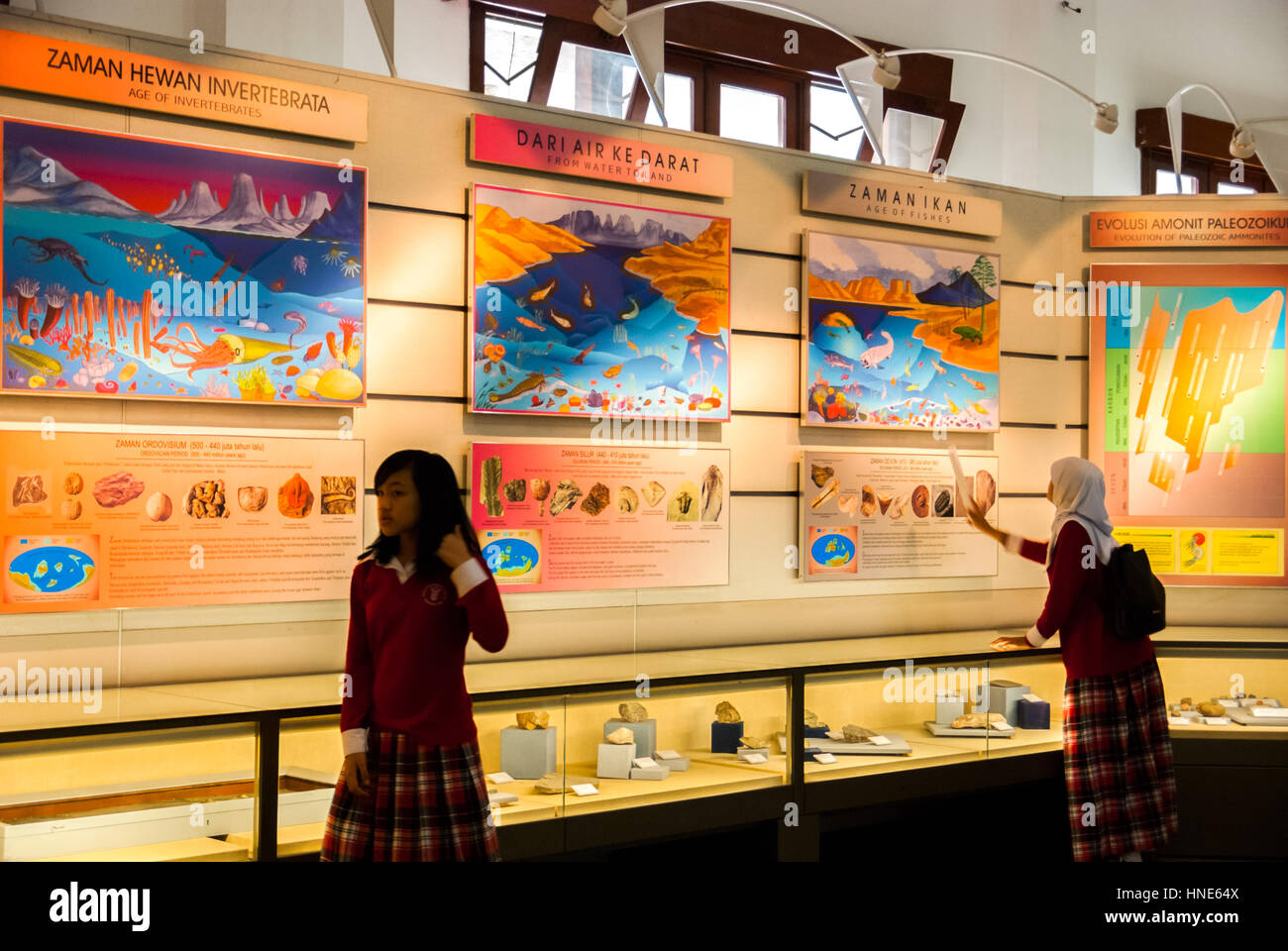 Kinder, die Studenten besuchen, werden im Geologiemuseum in Bandung, Indonesien, vor dem Hintergrund großer Informationstafeln fotografiert. Stockfoto