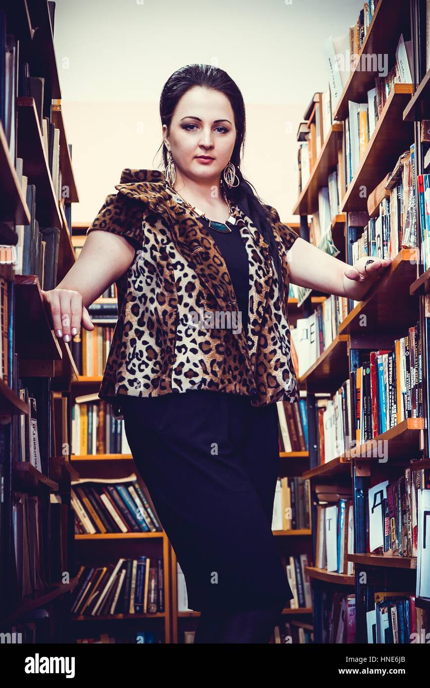 Junge Frau posiert für die Kamera in Bibliothek Stockfoto