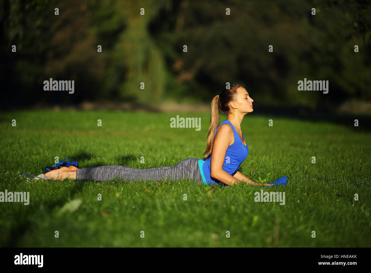 Junge Frau praktizieren Yoga auf der Matte in einem Natur-Hintergrund Stockfoto
