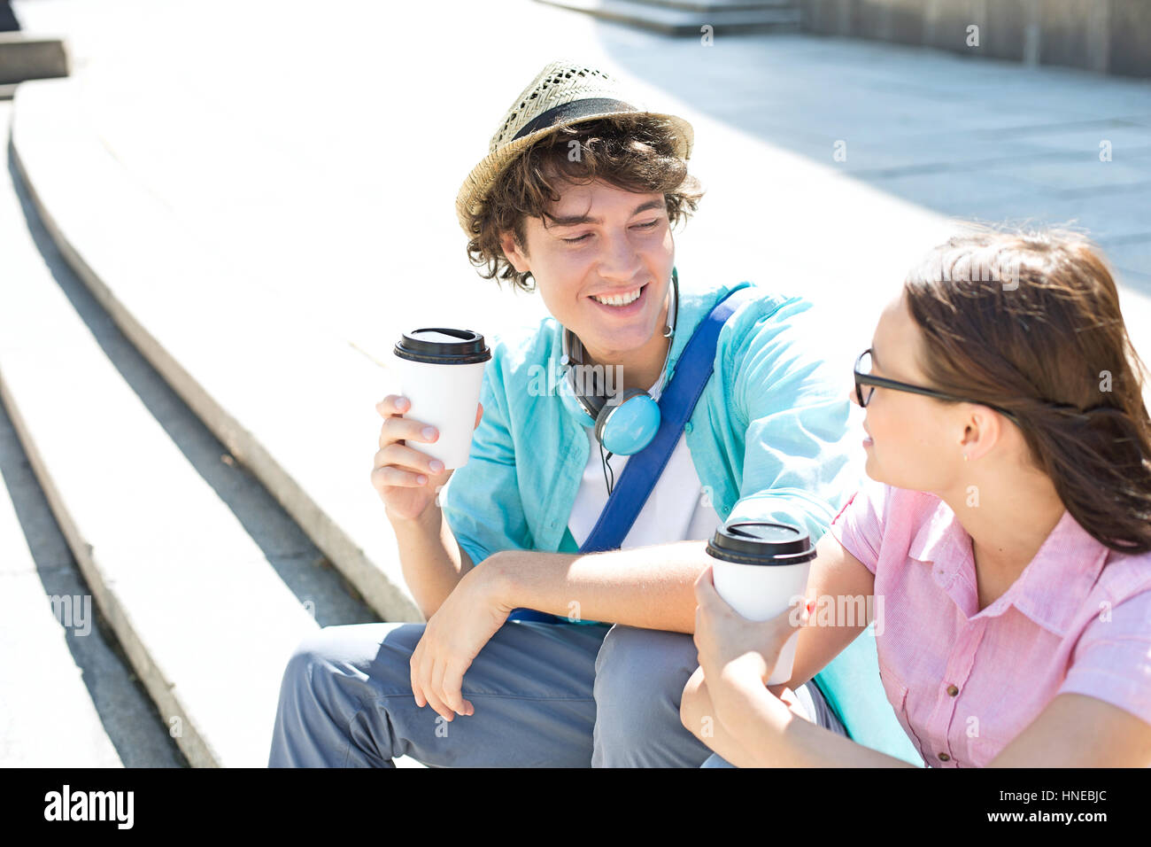Glückliche Freunde halten Einweg Kaffeetassen auf Schritte im freien sitzend Stockfoto