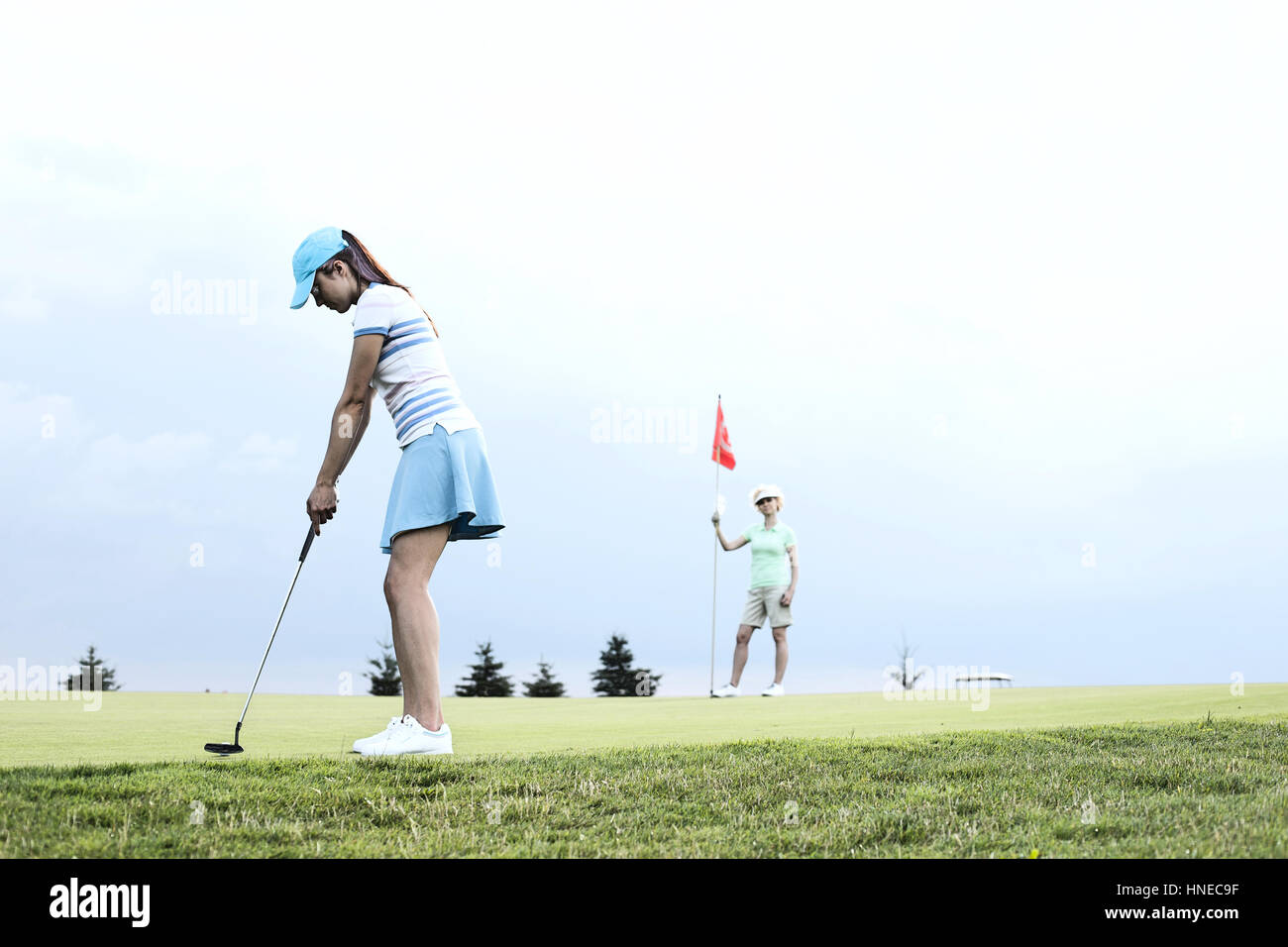 Frau spielt Golf mit Freundin gegen Himmel Stockfoto