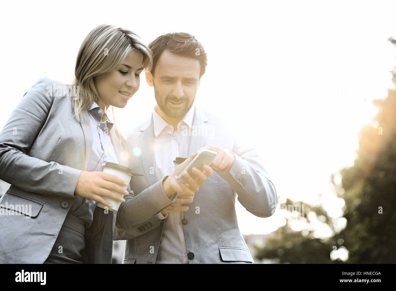 Business-paar im Gespräch bei der Verwendung von Handy auf sonnigen Tag Stockfoto