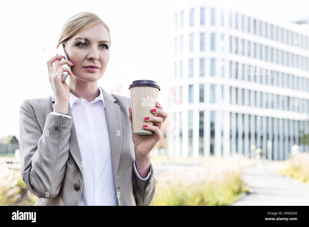Geschäftsfrau mit Handy halten Sie Einweg-Cup im freien Stockfoto