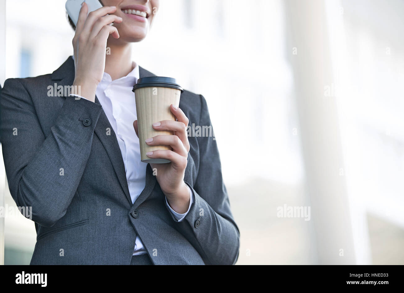 Mittelteil der Geschäftsfrau mit Handy halten Sie Einweg-Cup im freien Stockfoto
