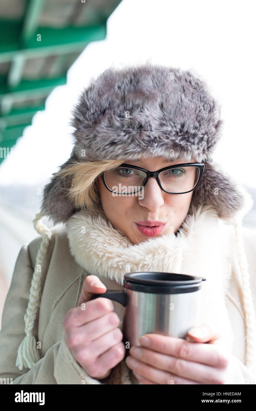 Porträt der Frau bläst Kaffee in isolierten Getränkeverpackung im winter Stockfoto