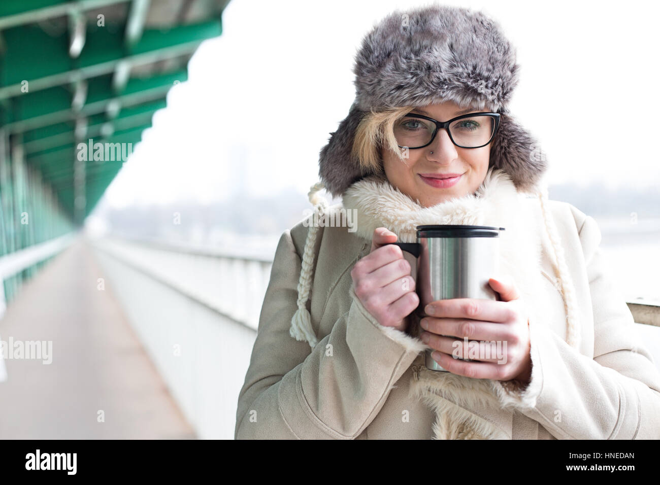 Porträt der lächelnde Frau in warme Kleidung mit isolierten Getränkeverpackung Stockfoto