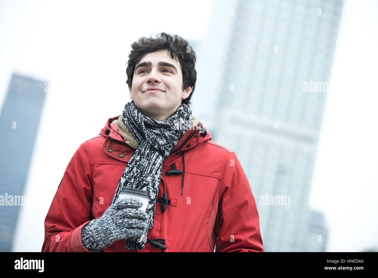 Lächelnd Mann in warme Kleidung wegsehen Einweg-Cup im Freien halten Stockfoto