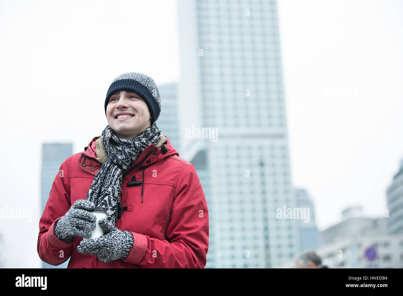 Glücklicher Mensch in warme Kleidung Einweg-Cup im Freien halten Stockfoto