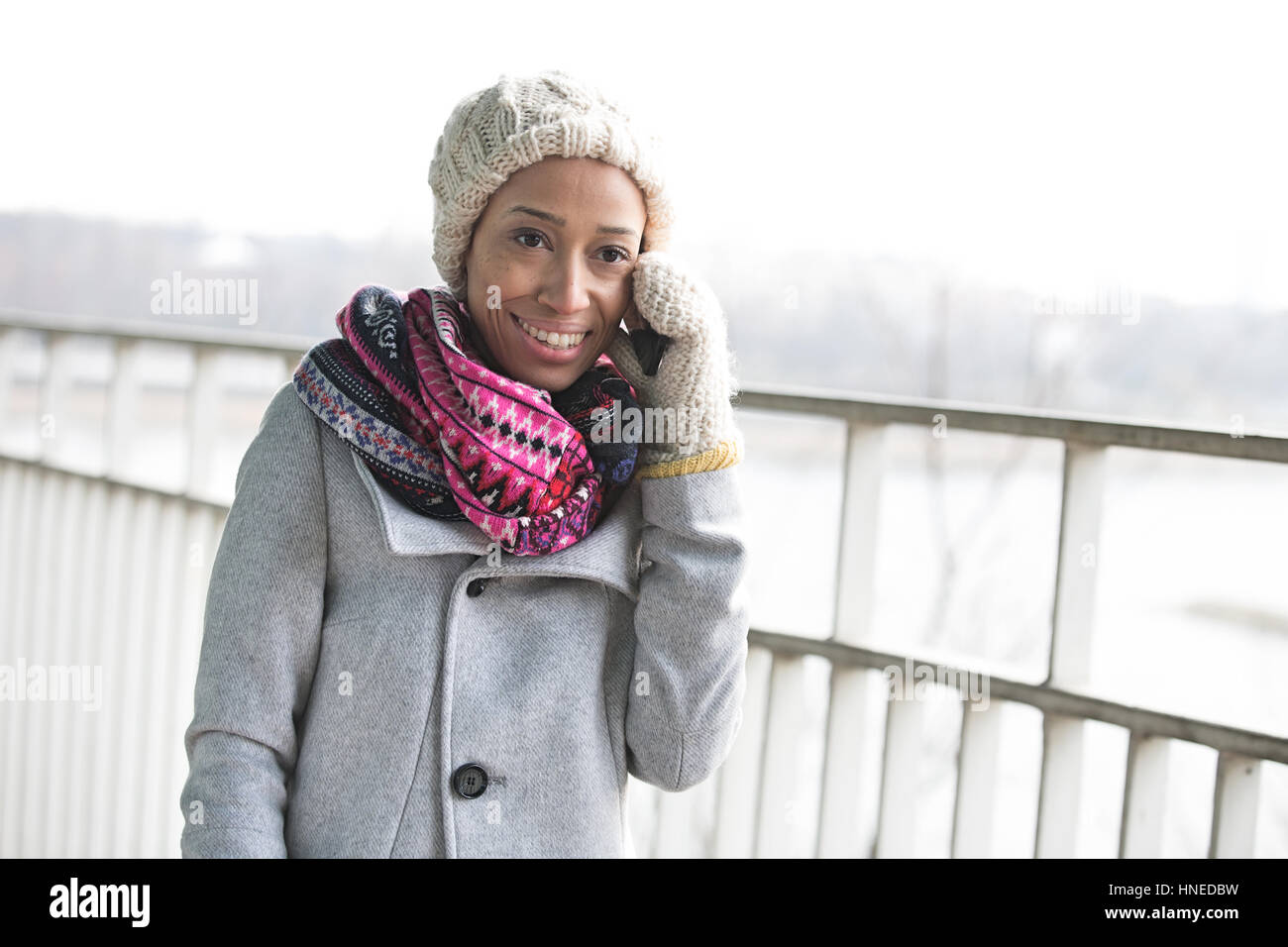 Glückliche Frau in Winterkleidung mit Handy im freien Stockfoto