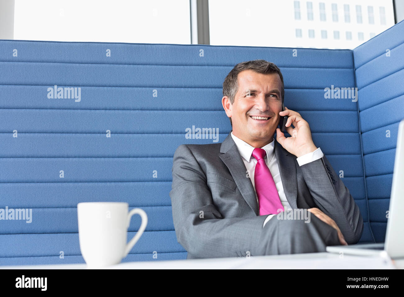 Lächelnde reifer Geschäftsmann reden über Handy im Büro Stockfoto