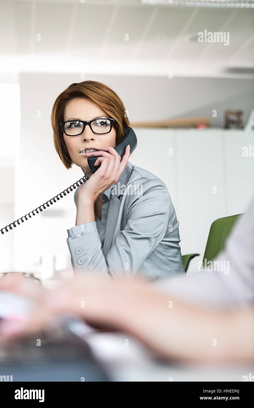 Junge Geschäftsfrau mit Telefon im Büro Stockfoto