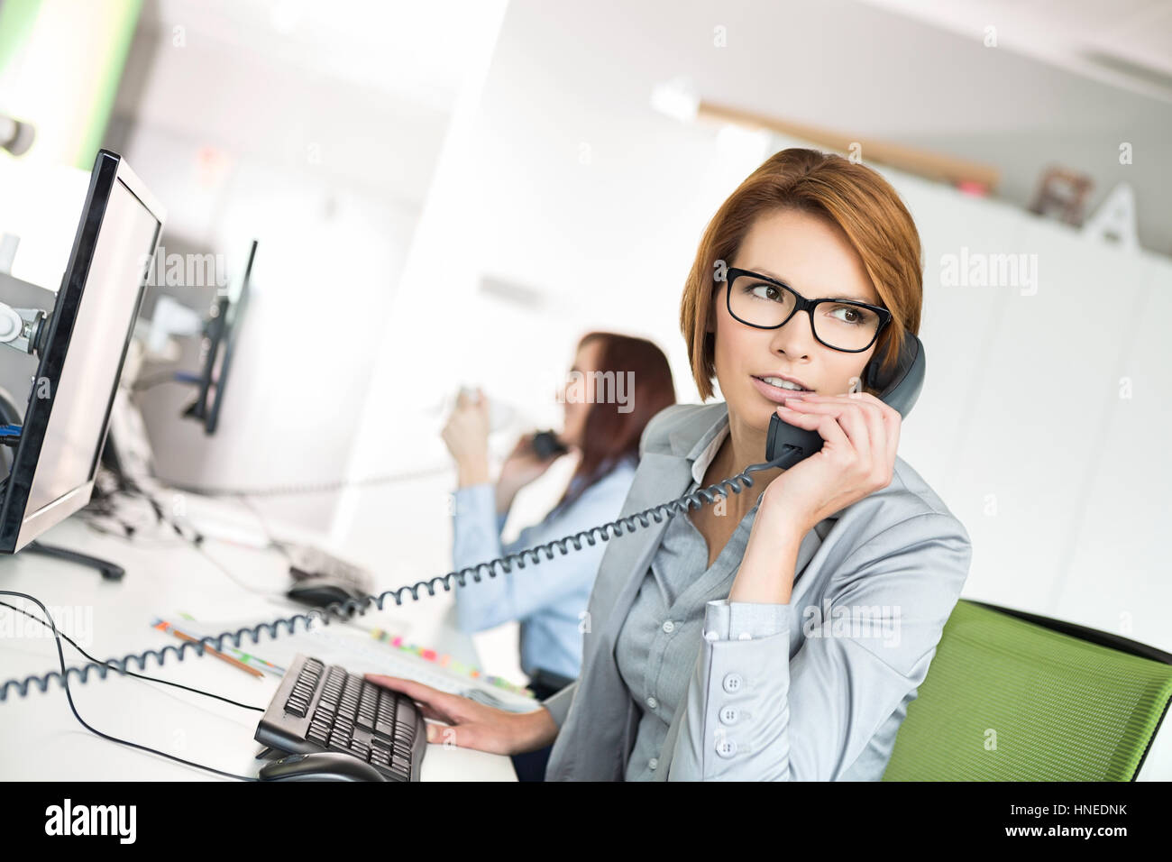 Junge Unternehmerin am Schreibtisch im Büro am Telefon sprechen Stockfoto