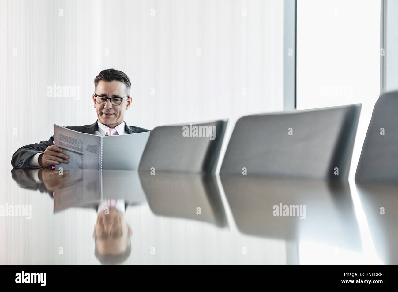 Im mittleren Alter Geschäftsmann Lesebuch am Konferenztisch Stockfoto