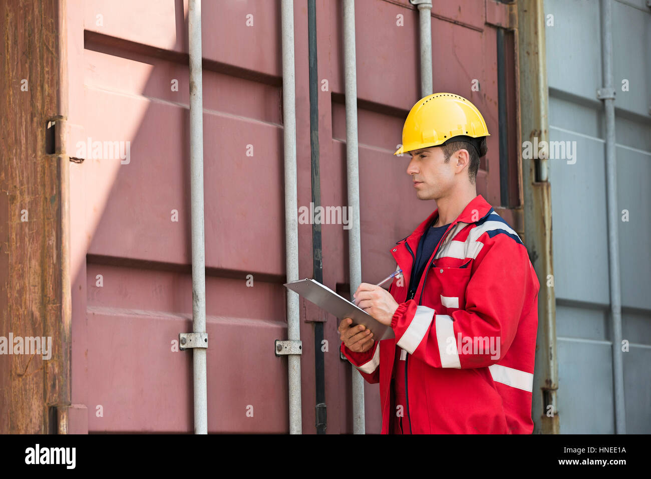 Männliche Arbeiter Frachtcontainer während des Schreibens in Zwischenablage im Frachthafen Inspektion Stockfoto