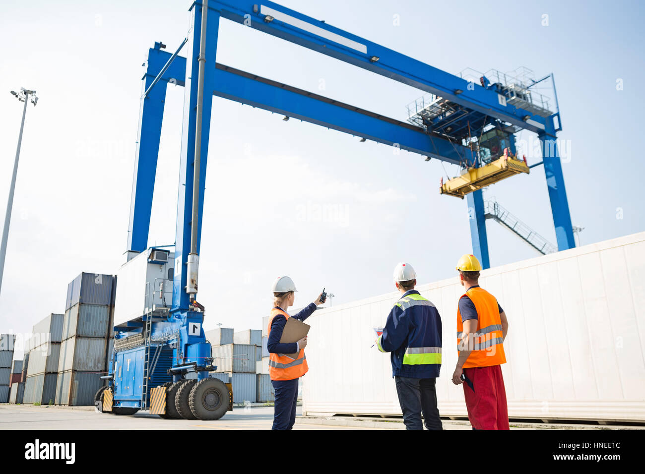 Arbeiter gegen Großkran laden Container am Frachthafen diskutieren Stockfoto
